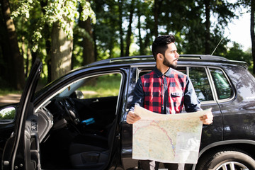 Photo of a traveler parked his car by the side of a road, lost and reading the map.