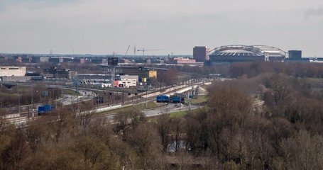 Timelapse video of traffic on the highway and trains passing by along the south side of Amsterdam. The soccer stadium 'Arena' can be seen in the distance. - Powered by Adobe