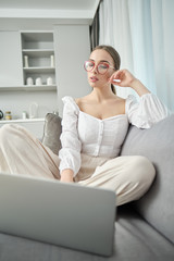 casual beautiful woman working on a laptop sitting on the bed in the house.