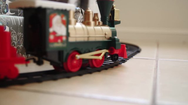 Toy train moving past Christmas presents, slow motion