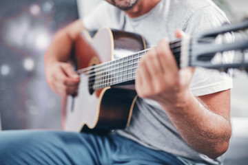 Man playing acoustic guitar in the living room.