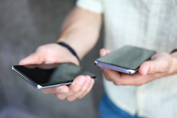 Focus on male hands holding two stylish sensory cellphone. Guy comparing, choosing desired gadget or making sharing data between mobile phones. Empty copy space on screens