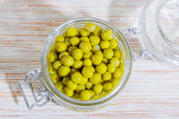 Home canning of summer bean crop, vegetable vegetarian diet healthy food, natural green peas marinated in a glass jar top view on table background