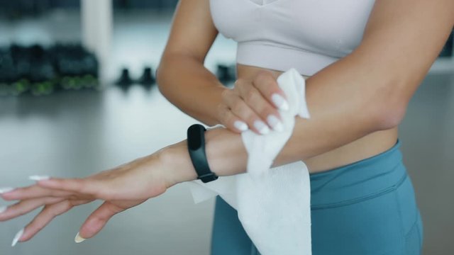Woman wipes her hands with a wet napkin in a fitness center