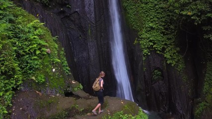 Woman walks through and  enjoying view at the waterfall in Bali island, Indonesia
