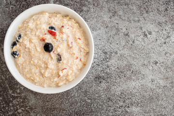 top view of cereal bowl filled with Bircher muesli with blueberries and cranberries on stone kitchen counter