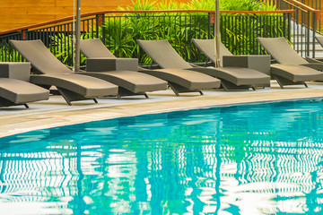 Umbrella and chair sofa around outdoor swimming pool in hotel resort for holiday vacation