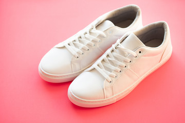 Stylish white fashion sneakers on pink background.