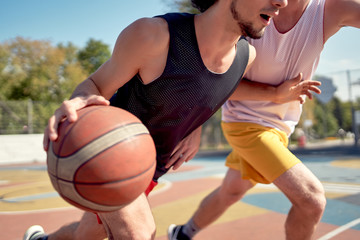 Photo of young athletes playing basketball on playground on summer day