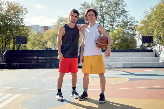 Full-length photo of two athletes with basketball on playground .