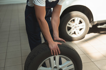 Fototapeta na wymiar strong hands of mechanic holding flat tire in car service department