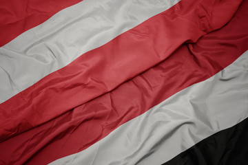 waving colorful flag of yemen and national flag of austria.