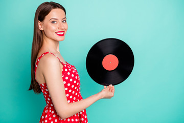 Portrait of lovely girl holding vinyl record disc smiling wearing dotted dresss skirt isolated over green teal turquoise background