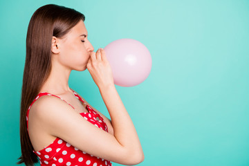 Profile side photo of upset lady trying to inflating balon wearing polka dot dress isolated over teal turquoise background © deagreez
