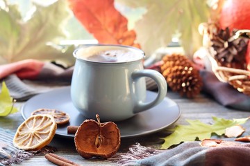 Cup of coffee, pumpkins, leaves, spices, a scarf on a wooden surface on a window background, home comfort concept, Thanksgiving, autumn season