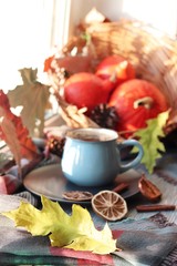 Cup of coffee, pumpkins, leaves, spices, a scarf on a wooden surface on a window background, home comfort concept, Thanksgiving, autumn season