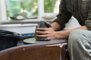 The master creates products from gray clay on a potter's wheel. Girl creates a ceramic vase