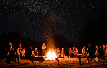 beautiful scenery of night vision. bonfire around people. basking by the fire at night. the concept of outdoor activities. - obrazy, fototapety, plakaty