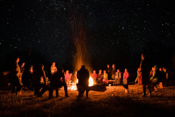 beautiful scenery of night vision. bonfire around people. basking by the fire at night. the concept of outdoor activities. - obrazy, fototapety, plakaty