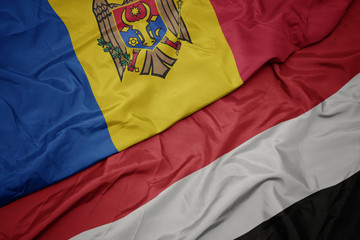 waving colorful flag of yemen and national flag of moldova.