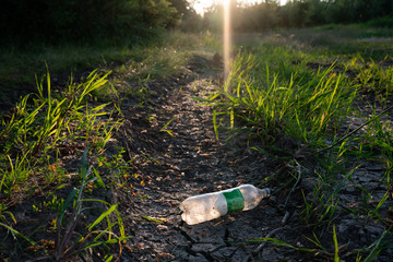 Empty old plastic bottle on the cracked dry ground