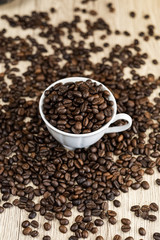 Coffee beans in coffee cup on wood table background.
