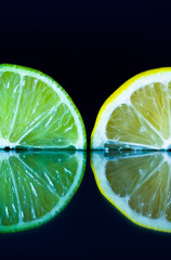 Lime and lemon slice on black reflective background. Creative food concept, minimal style.