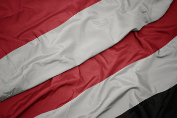 waving colorful flag of yemen and national flag of indonesia.