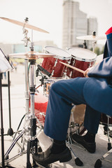 Fototapeta na wymiar Orchestra musician - drummer in a blue suit closeup plays a drum set during an outdoor concert