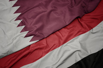 waving colorful flag of yemen and national flag of qatar.