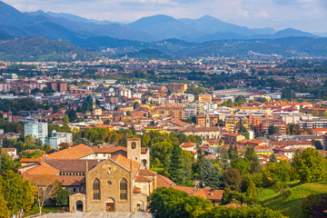 Fototapeta na wymiar Picturesque aerial view of Bergamo city, Lombardy, Italy. Bergamo Alps (Alpi Orobie) begin immediately north of the city, on the background