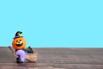 Happy Halloween concept.Pumpkin head doll in witch costume with a broom. Pumpkin head doll on a wood floor, isolated blue background and clipping path.Front view and copy space for text.