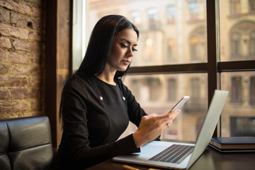 Woman successful marketing coordinator sending sms via mobile phone during online distance work on...