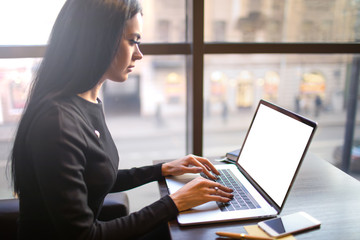 Serious woman skilled marketing coordinator typing on pc laptop computer with empty mockup copy...