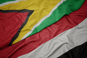 waving colorful flag of yemen and national flag of guyana.