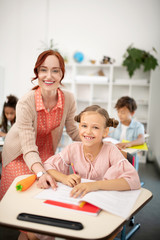 Cheerful schoolgirl smiling broadly while having interesting lesson