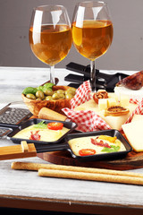 Delicious traditional Swiss melted raclette cheese on diced boiled or baked potato and baguette served in individual skillets with salami..
