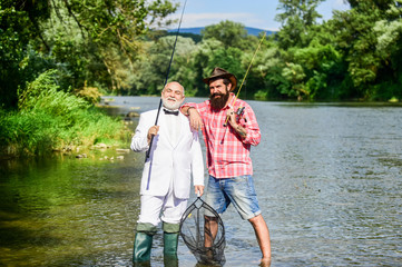 Look what we caught. retired father and mature son with beard. Fly fishing adventures. happy fishermen in water. friends men with fishing rod and net. hobby of businessman. retirement fishery