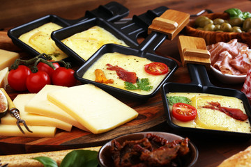 Delicious traditional Swiss melted raclette cheese on diced boiled or baked potato and baguette served in individual skillets with salami..