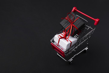 Naklejka premium Shopping cart with gifts on dark background