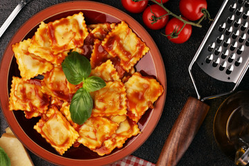 Ravioli with tomato sauce garnished with parmesan cheese and basil on rustic table
