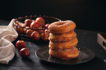 Stack of assorted donuts on a plate with milk on black background