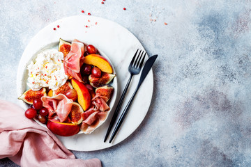 Summer fruit salad with burrata, peaches, figs, grapes, jamon or prosciutto. Top view, overhead, copy space