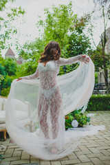 Seductive young bride in white negligee dancing with big piece of white fabric