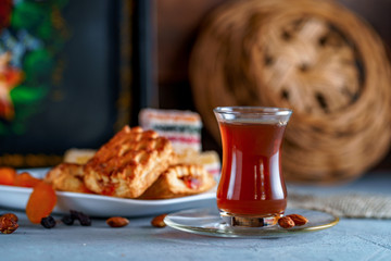 Turkish tea in an authentic glass with sweets, dried fruits and nuts for a teatime
