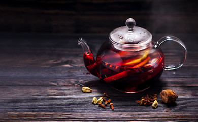Hot wine mulled wine with spices in a glass teapot on a wooden table and space for text. Winter...