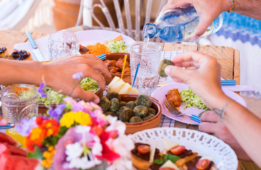 Group of hands sharing food and drink. Caucasian peoples enjoying brunch or meal together. Fruits and vegetables on the wooden table. Sunlight outdoor on the terrace