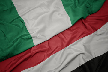 waving colorful flag of yemen and national flag of nigeria.