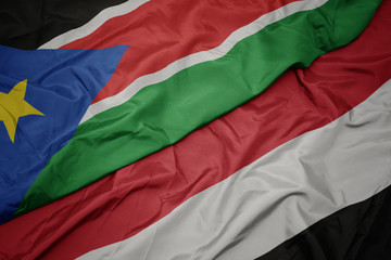 waving colorful flag of yemen and national flag of south sudan.
