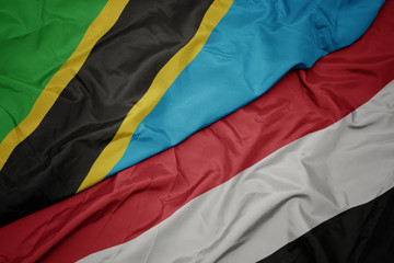 waving colorful flag of yemen and national flag of tanzania.